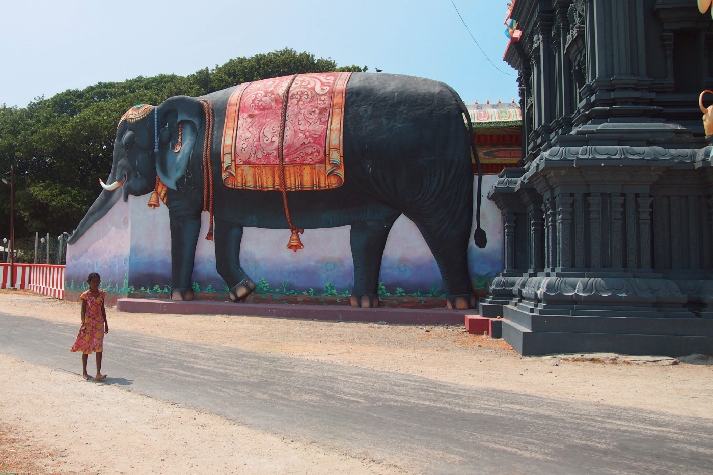 Jaffna Sri Lanka. Sri Lankan girl in a dress walking past a giantblack elephant statue at a temple