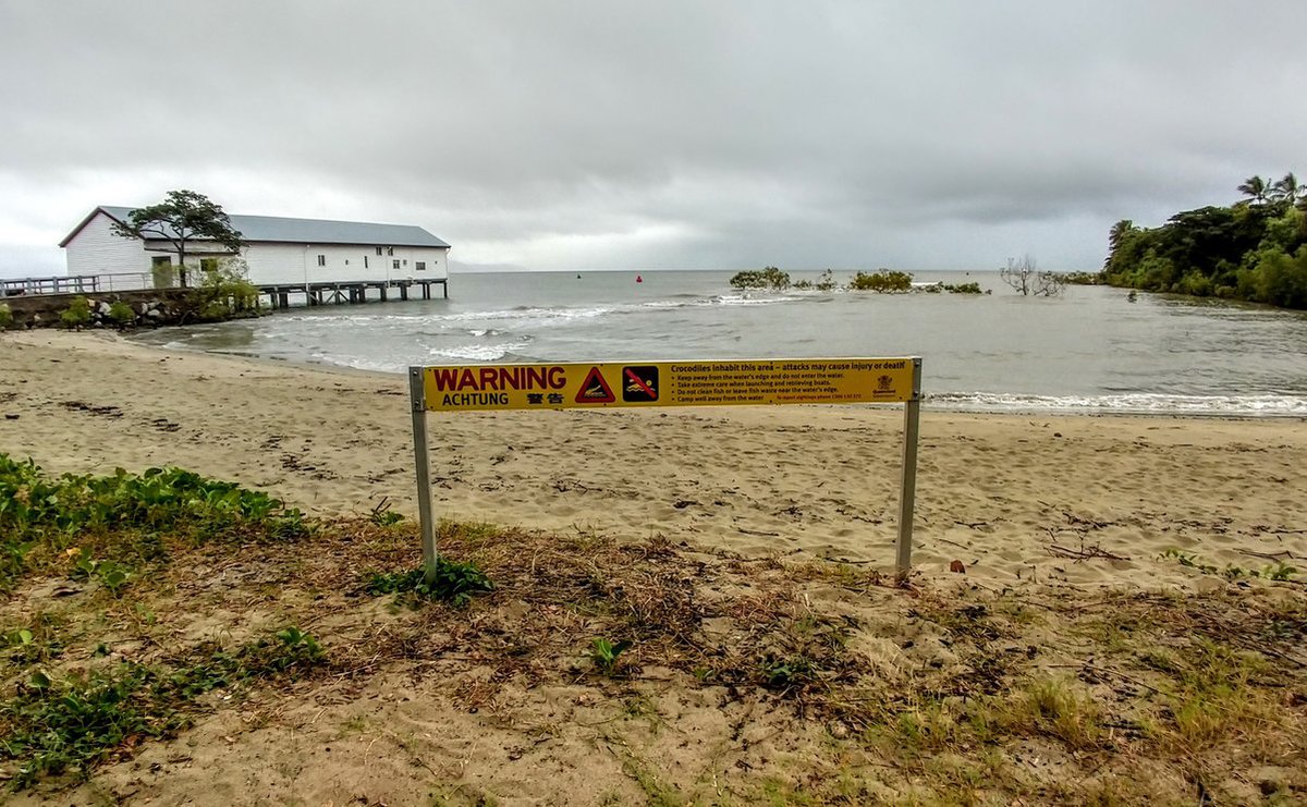 Port Douglas in winter. Storm and rain on the beach and crocodile warning sign