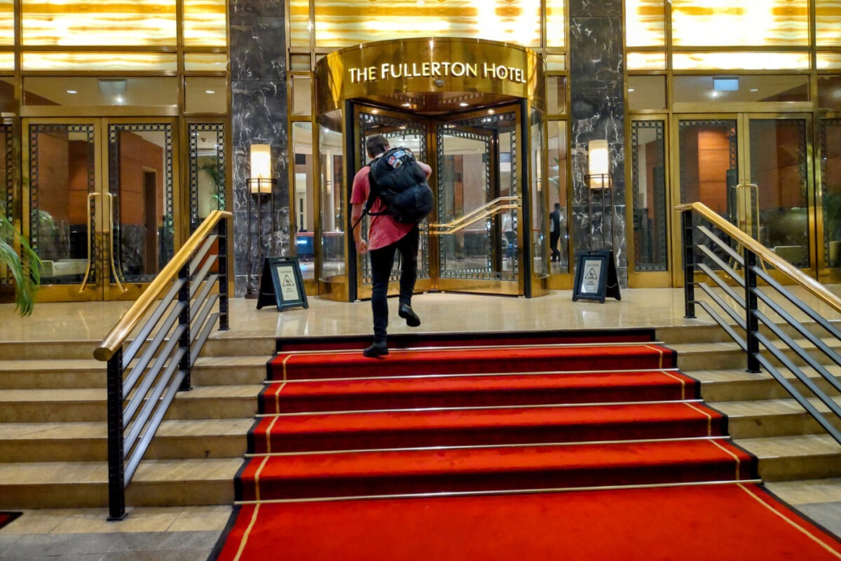 Teenager entering the fullerton hotel in Singapore dressed as a backpacker