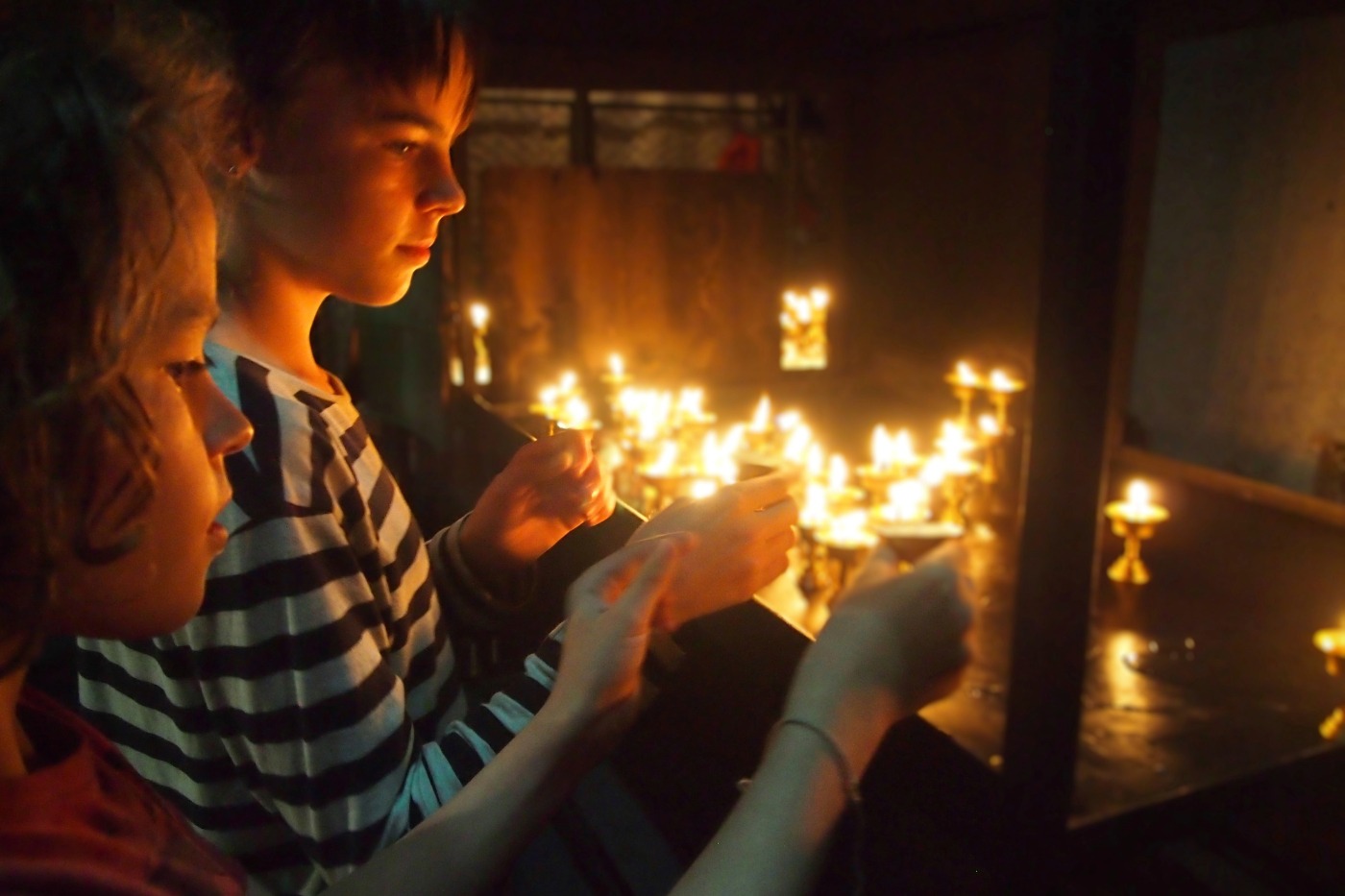 tourist children lighting candles at a temple in nepal