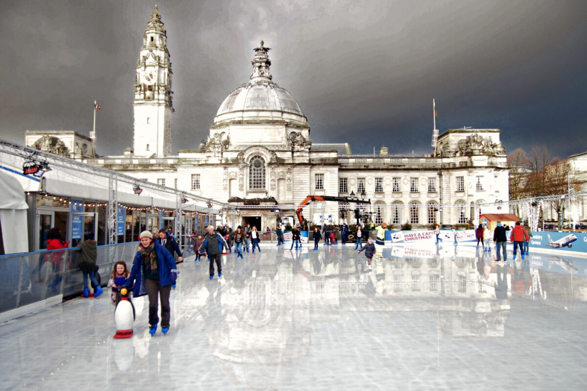 Families skating on an ice rink in central Cardiff in front of City Hall.