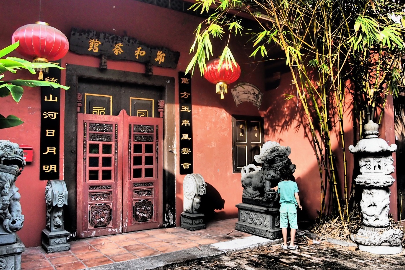Small child in Malacca Old Town Malaysia looking at a Chinese lion statue and beautiful doorway